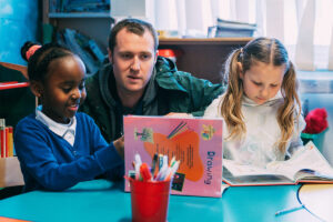 Two Children Reading With Teacher